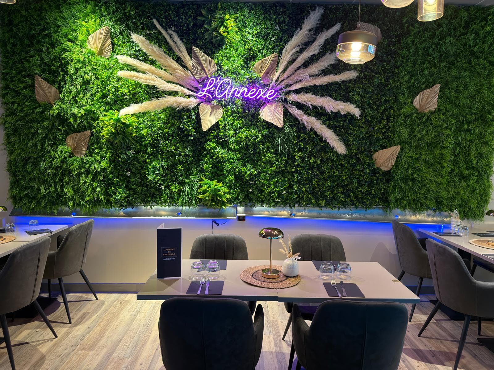 Salle du restaurant L’Annexe à Beauvais : mur végétal, enseigne néon L’Annexe et tables dressées
