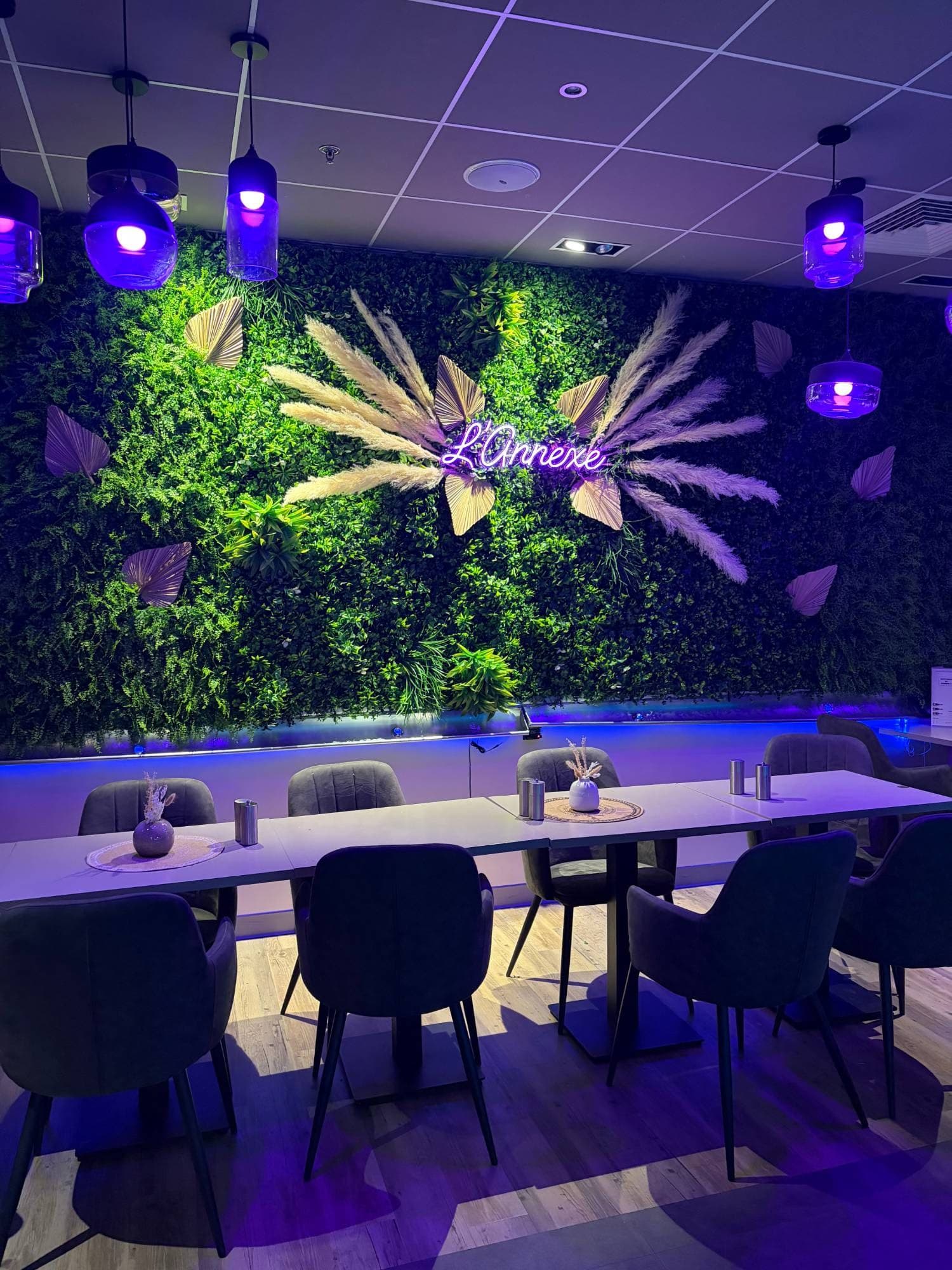 Salle du restaurant L’Annexe à Beauvais avec son mur végétal et l’enseigne néon L’Annexe